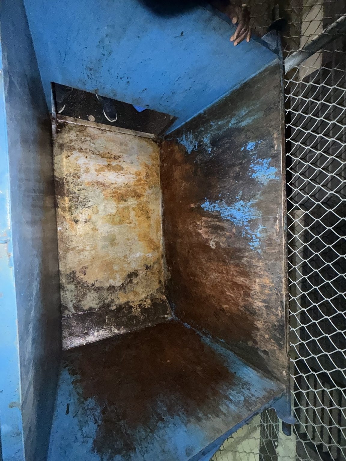 Inside of a metal container before laser restoration with rust, oxidation, and damaged paint on the walls