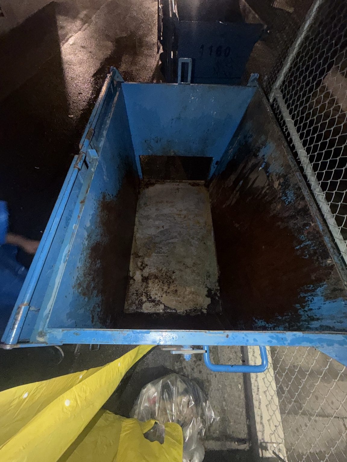 Open metal container before laser restoration with stained bottom, rusted walls, and damaged blue paint