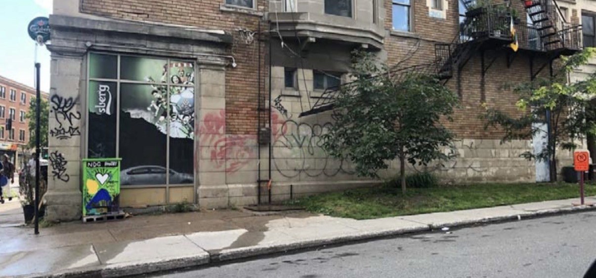 Graffitis noirs, rouges et verts sur la façade en pierre du secteur Harvard à Montréal avant intervention