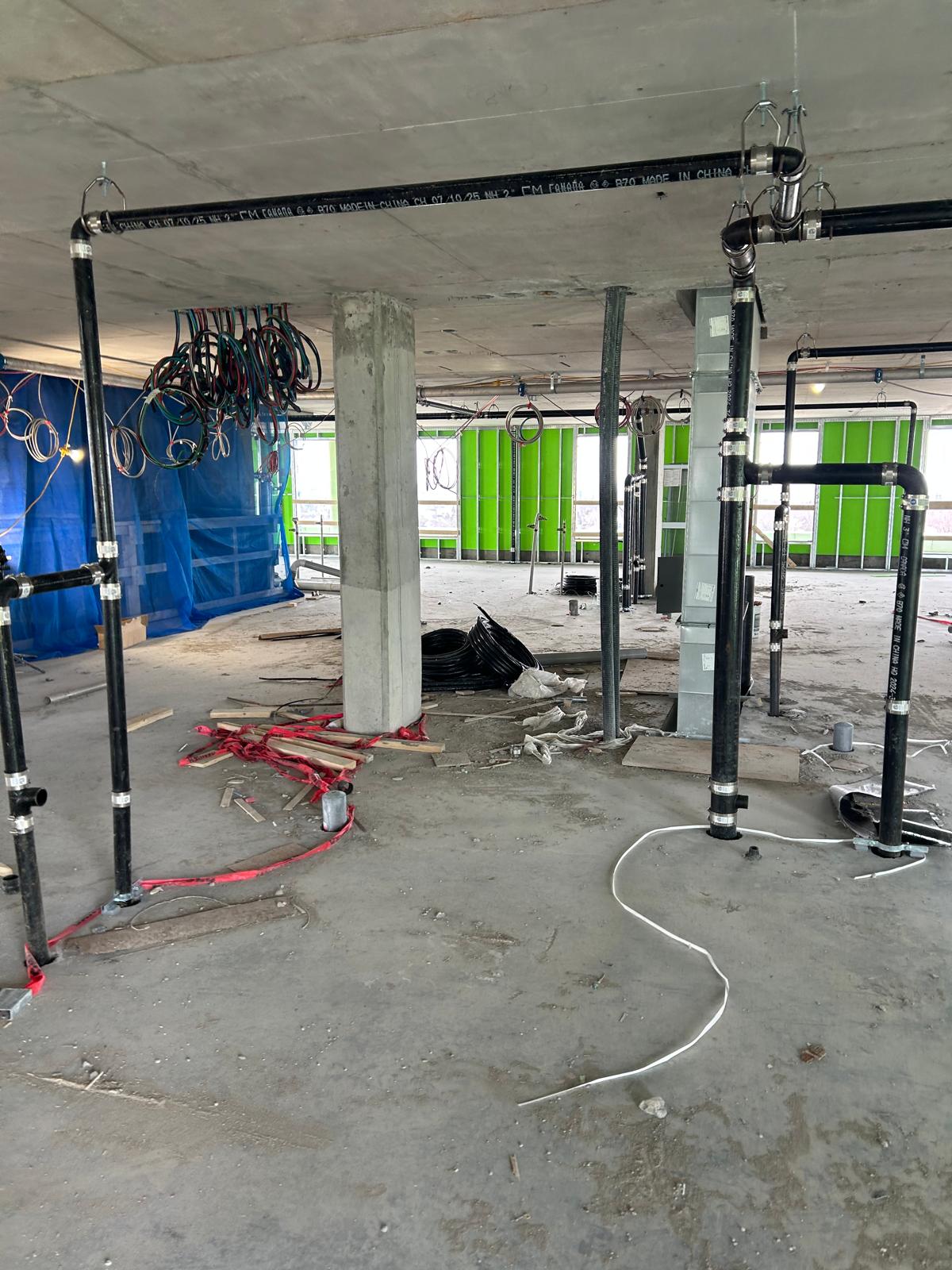 Zone de services avant nettoyage de chantier avec retailles, gaines et salissures au sol
