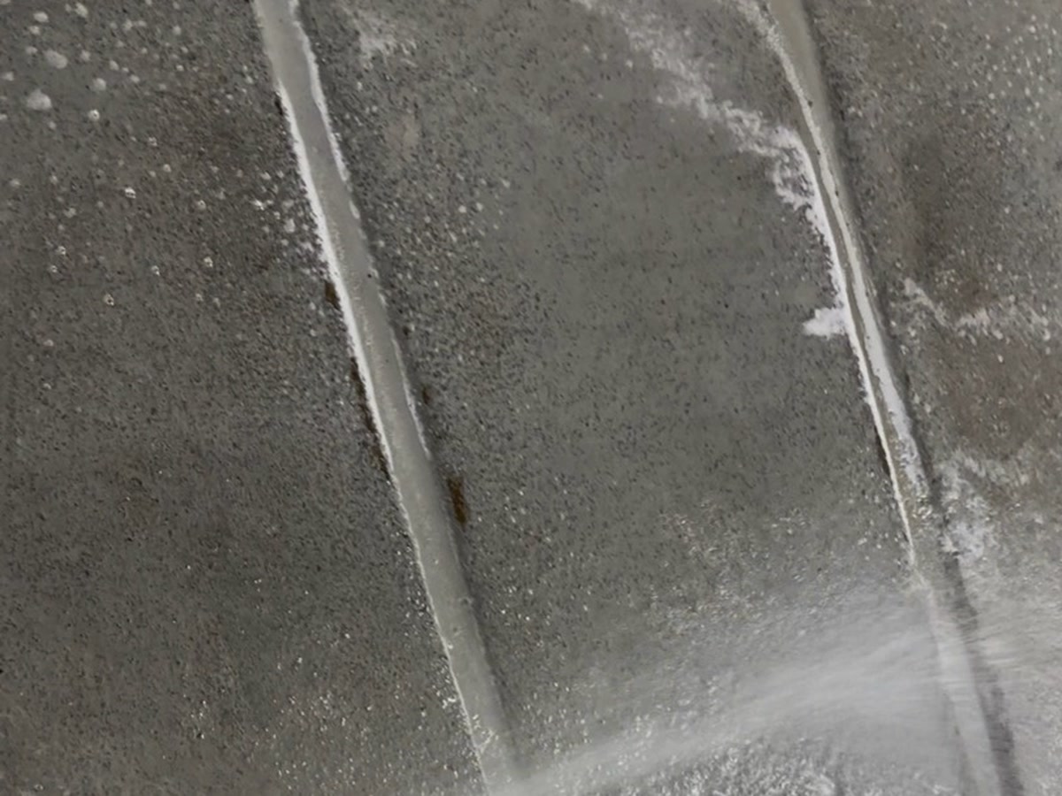 Rinçage à pression du dégraissant sur la rampe de circulation d'un garage souterrain à Montréal