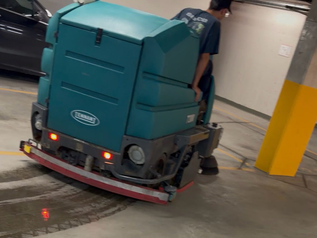 Tennant T7300 effectuant le récurage mécanique d'une voie dans un stationnement souterrain occupé à Montréal