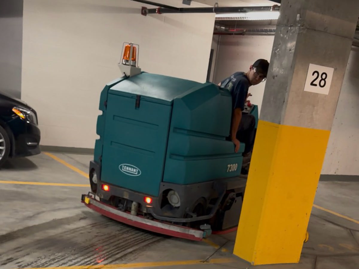 Tennant T7300 récupérant l'eau et les résidus pendant le récurage d'une voie du garage
