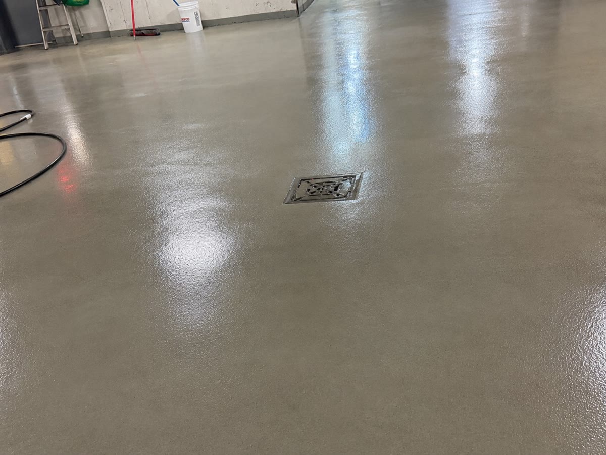Vue rapprochée de la même zone générale autour du drain, avec la dalle encore mouillée pendant l'évacuation de l'eau